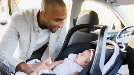 dad and girl in a car seat smiling at each other