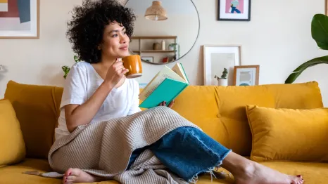 woman sitting on a couch with a cup of coffee and a book