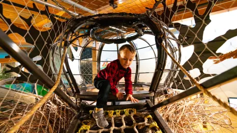young child climbing in a rope climber at Hands on Children's Museum, which is hosting spring break activities this weekend