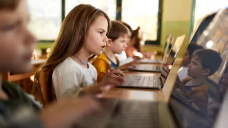 young girl studying on laptop in classroom