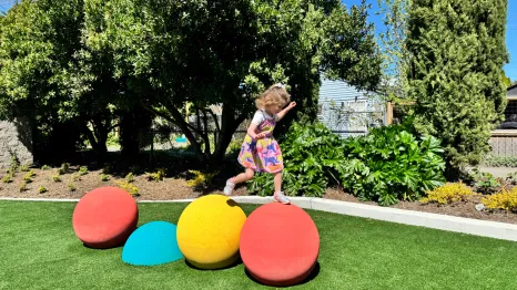 young girl hopping across bright play structure at a new playground opening this weekend in Seattle