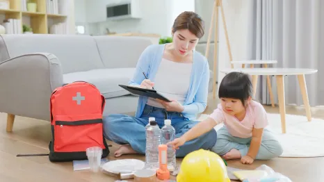 mom and daughter packing an emergency backpack with supplies