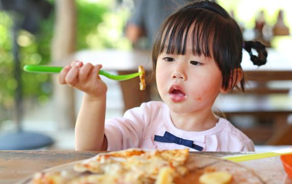 little girl eating at restaurant during a kids eat free deal