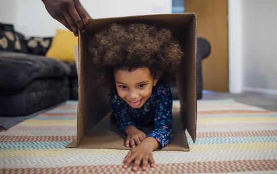 a child crawls through a cardboard box, part of an indoor obstacle course challenge