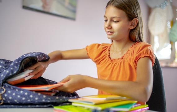 Kid-putting-books-in-backpack