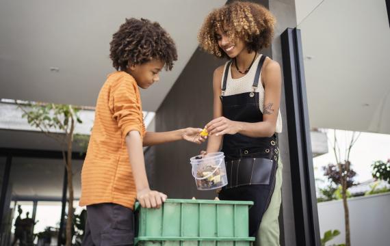 African american young woman and her younger brother making compost from leftovers.
