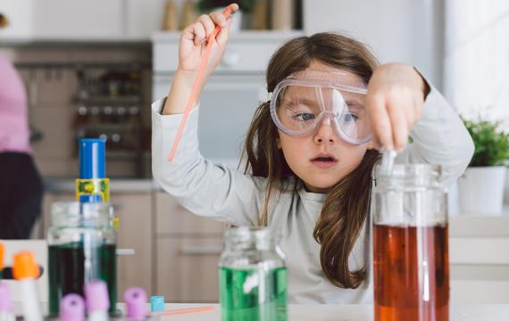 Girl filling test tube wearing goggles during an easy science experiment for kids