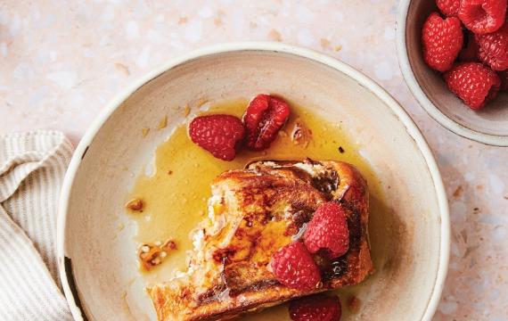 French toast on a plate with syrup and strawberries