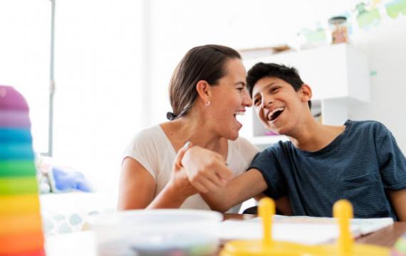 Mom and son with special needs sitting at a table smiling together