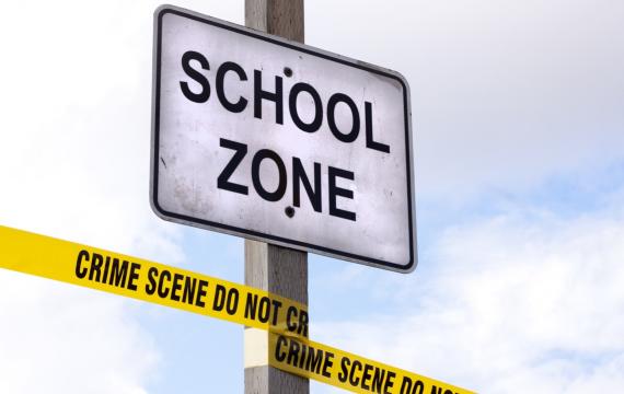 Closeup of School Zone sign with crime scene tape wrapped around it