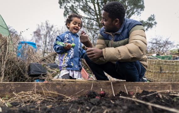 Father and young child working in a garden bed together