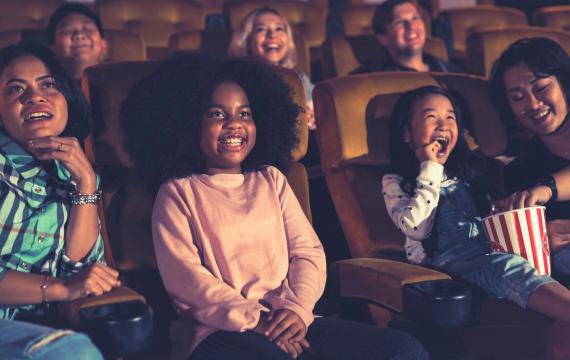 Happy kids in a movie theater watch a movie during cheap summer movie specials around Seattle