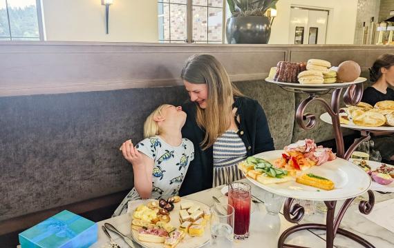 A mom and young daughter look at each other while enjoying an outing for fancy afternoon tea at the Lodge Saint Edward Park near Seattle; best afternoon tea outings with kids