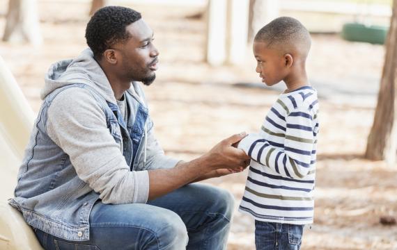 Dad talking with his son and holding his hands