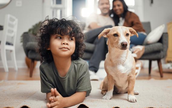 Little boy laying on the floor on his stomach next to a small dog
