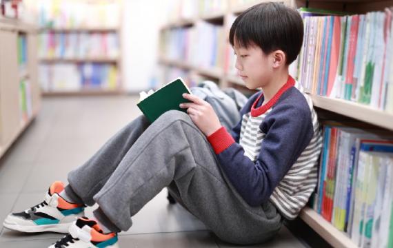 Kid-reading-book-in-library