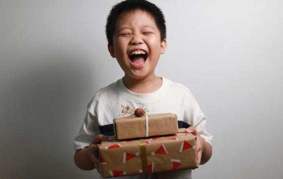 Young boy holding two packages with a big smile and eyes closed