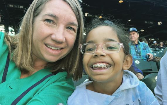 Mother and daughter smiling at a Mariner's baseball game