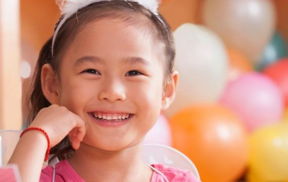 Smiling girl with birthday balloons behind her