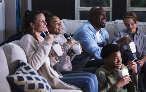 Family watching TV and eating takeout