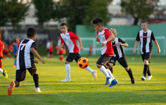 Kids of about middle school age, young teens, play in a soccer match while parents and families look on top tips for being a good sports parent