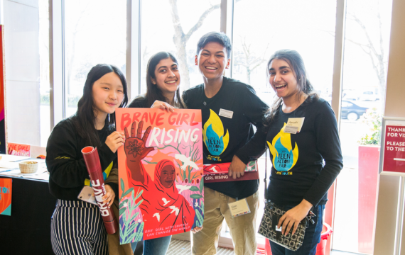 Group of teens standing together with a "Brave Girl rising" poster