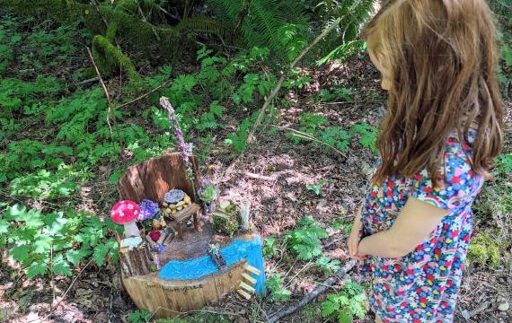 At the Sammamish Fairy House Trail by Beaver Lake, a girl points to a fairy home