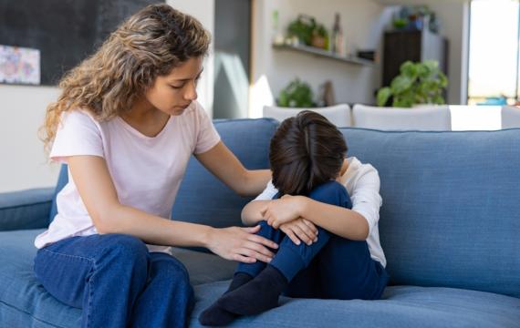 Mom comforting her son who is crying on a couch because he is a kid with anxiety