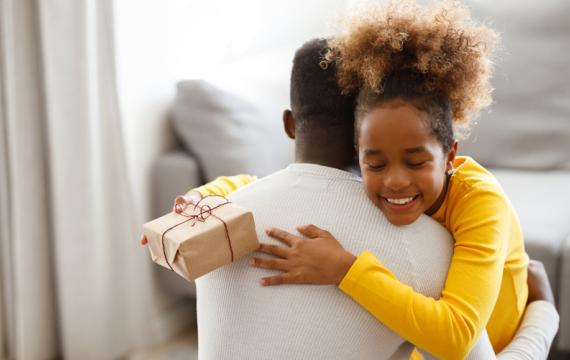 Girl hugging her dad and holding a gift 