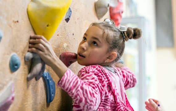 Girl rock-climbing at a mid-winter break camp in Seattle
