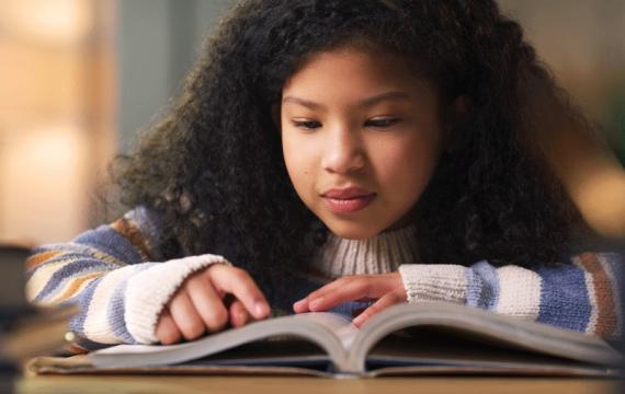 A young girl reads a book about science for kids