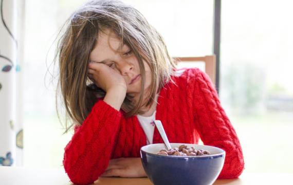 child sleeping at breakfast table who needs to adjust to daylight saving time change