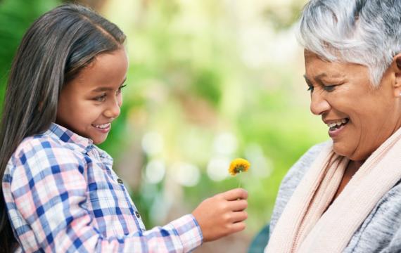 Young girl giving older woman a flower and spreading kindness