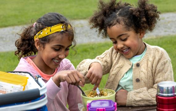 Two girls eating a healthy lunch at summer camp