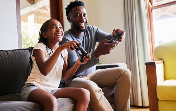 Dad and daughter playing video games having fun together