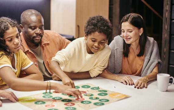 A family sitting at a table playing a board game on a family game night