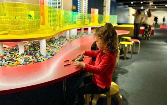 Young girl playing with loose Lego bricks at the new MOHAI Towers of Tomorrow exhibit