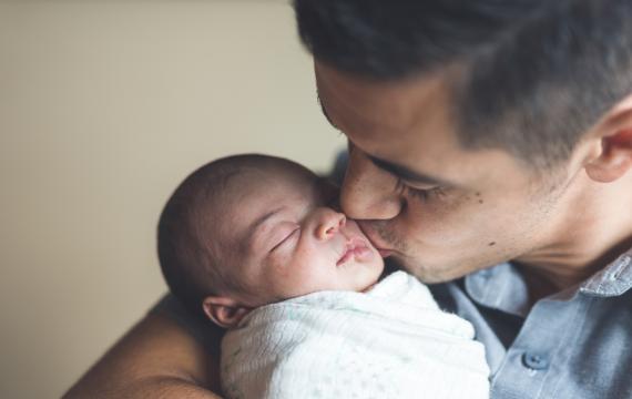 Dad kissing newborn baby