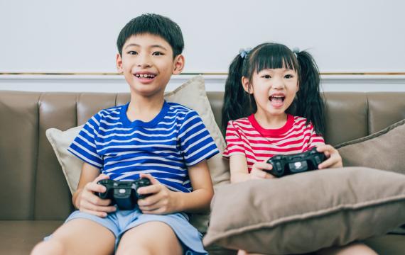 Boy and girl on the couch playing video games how to raise a healthy gamer