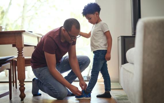 A dad helps his son try on shoes looking for the right size, one that fits