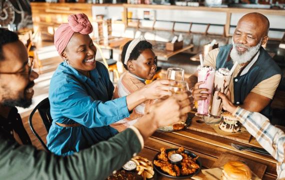 A family sitting at a kid-friendly brewery in Seattle, toasting with their drinks