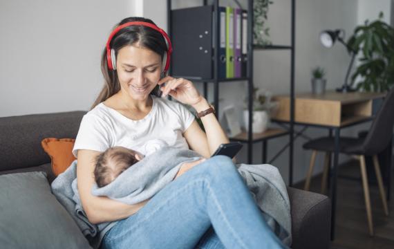 mom holding a baby and listening to a parenting podcast