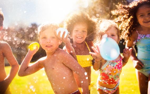 kids holding water balloons having fun with water in the summer outside