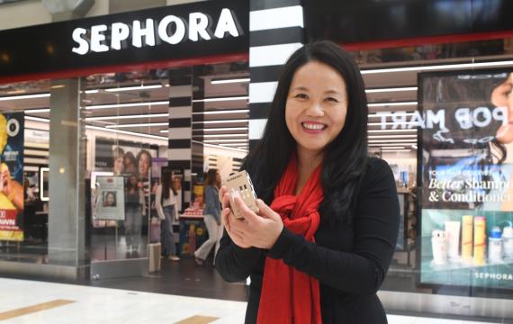 woman holding up a free gift from Sephora on her birthday