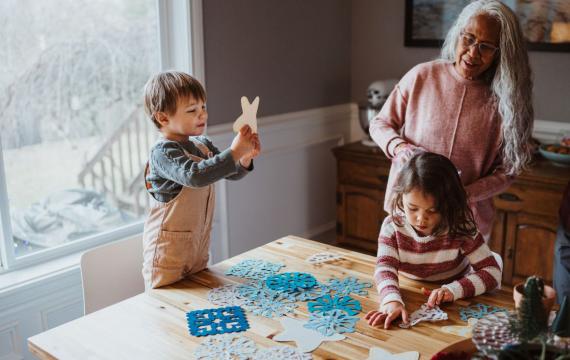 A family crafts snowflakes together in front of a window as a winter activity