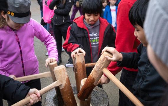 kids pounding mochi with wood mallets during Mochi Tsuki, a family-friendly festival happening this weekend near Seattle