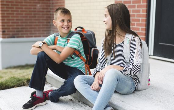 kids sitting on steps outside smiling at each other