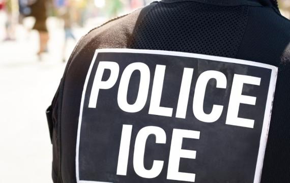 POLICE ICE marking on the back of a hi-visibility stab proof vest worn by a police officer