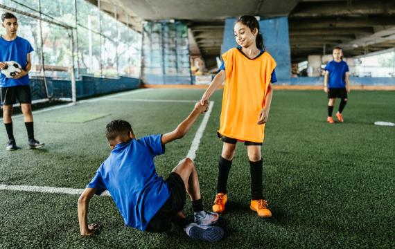 soccer player helping another player to their feet