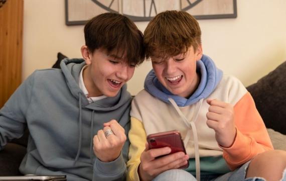 Two teenage boys playing and gambling on smart phones